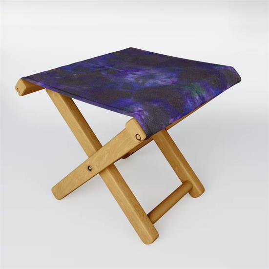 A wood folding stool featuring the Nebula dyeblot design for the seat.