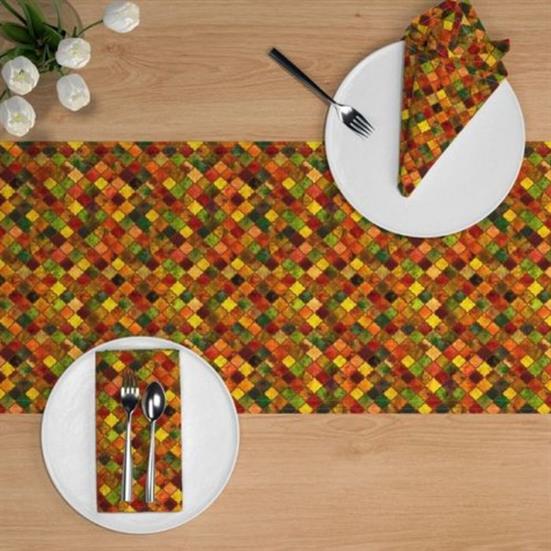 A table runner, and napkins, in an arabesque design featuring autumnal colors.