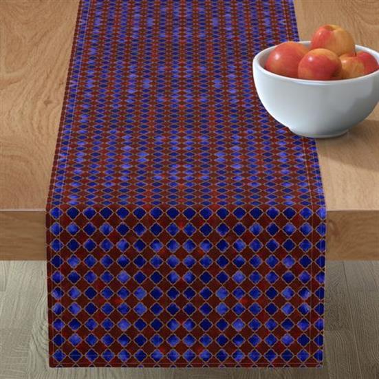 A table runner in an arabesque design with burgundy, blue and hints of gold.